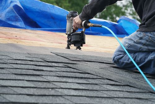 man using nail gun to install shingle to repair roof