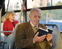 A Brazilian man reading the scriptures.  He is sitting on a bus.