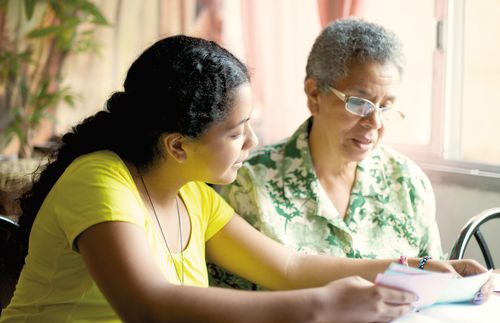 A young woman and elderly woman looking at family history papers.