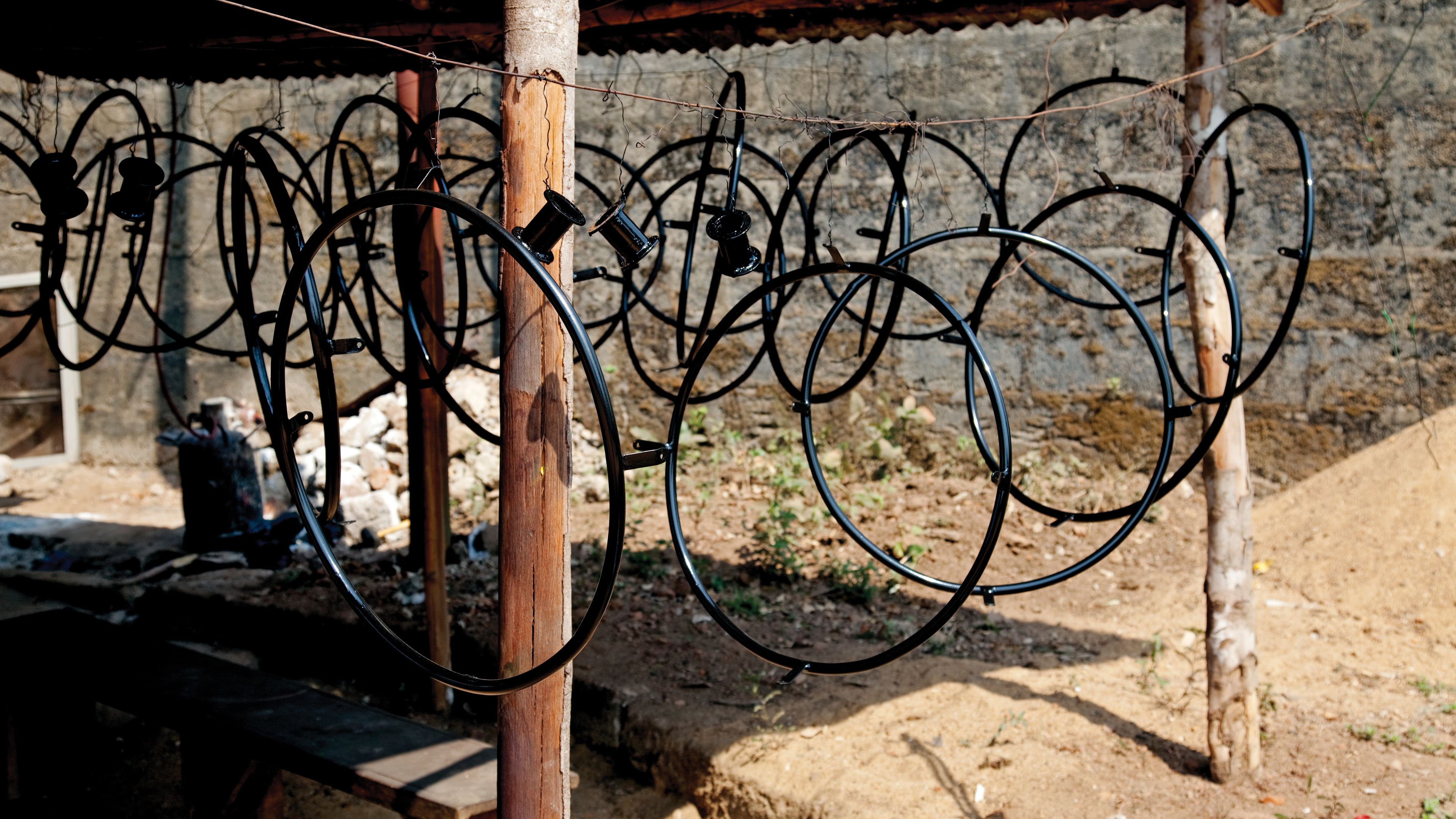 Many round wheelchair parts hanging down from a string in Africa.