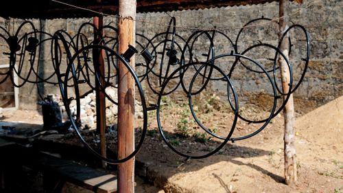 Many round black wheelchair parts hanging down from a horizontal string in Africa.