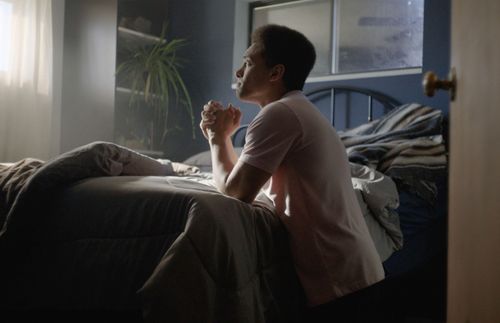 a young man kneeling by his bed and praying