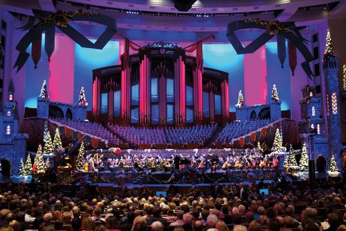An audience watching the Mormon Tabernacle Choir, orchestra, and dancers perform with a purple and blue backdrop at the Christmas concert in 2011.
