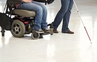 feet of person in wheelchair and of blind person with cane