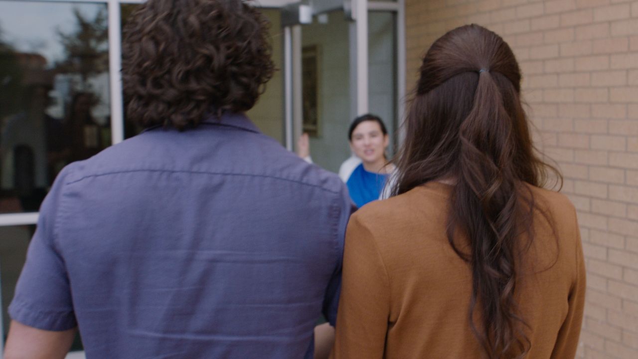 A married couple are greeted at the door by someone saving them a seat for church