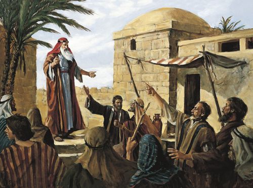 Lehi preaching to the people of Jerusalem. Several people are mocking and pointing their fingers at him.   Lehi is standing above them on a raised area.  There are palm trees and buildings in the background.