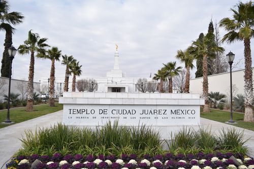 A view of the Ciudad Juárez Mexico Temple in the background, with the temple name sign and scenery in the foreground.