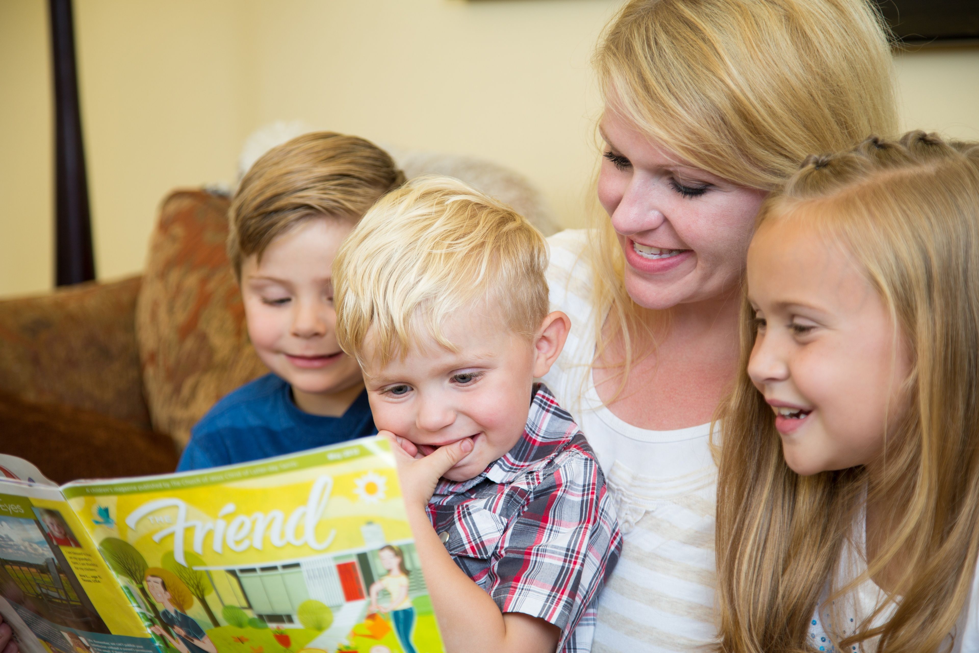 A mother reads the Friend magazine to her children.
