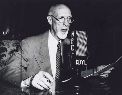President George Albert Smith sitting at a desk and speaking into a microphone labeled NBC and KDYL, the local Salt Lake radio station.