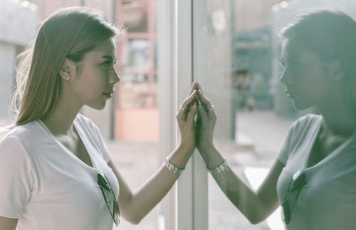 young adult woman looking at her reflection