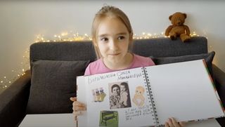 girl holding up photo album of her ancestors