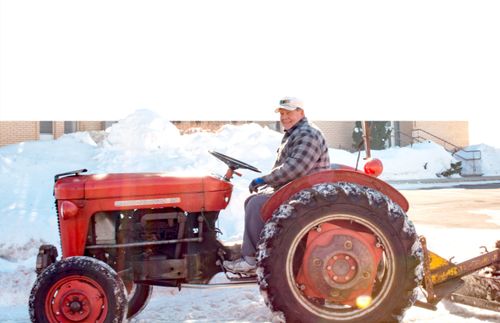 homem a limpar neve com trator