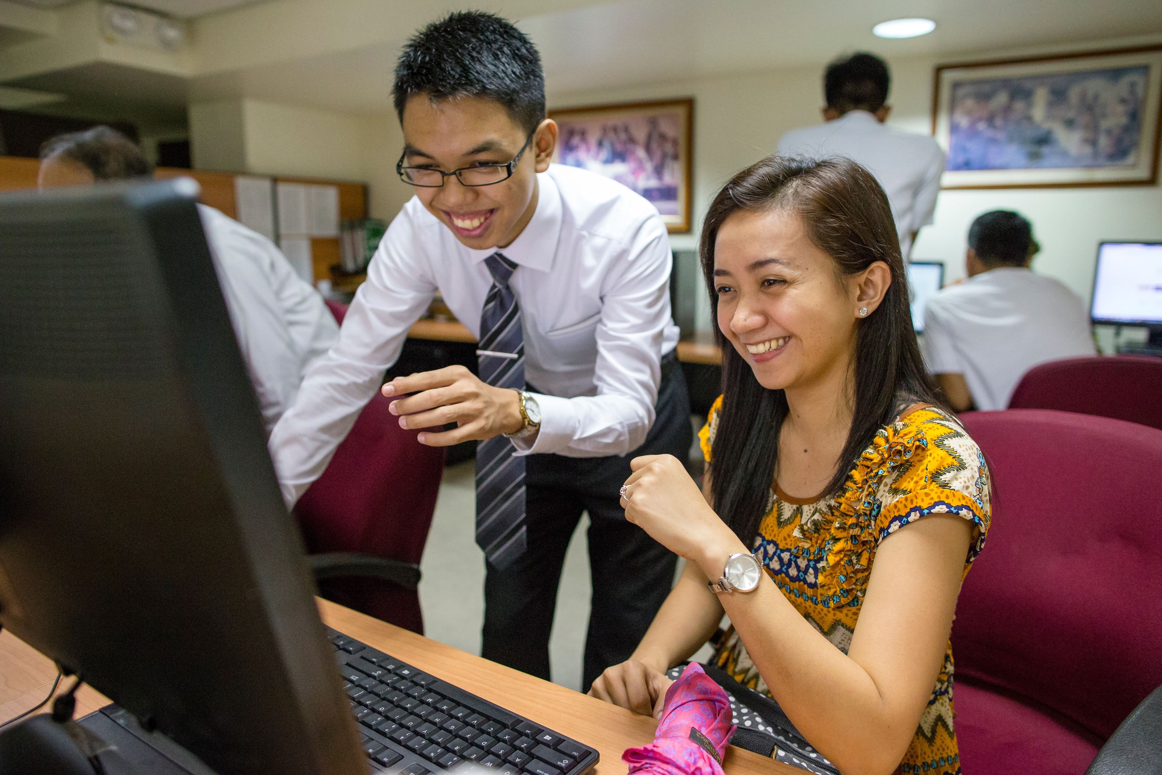 A group of youth work on family history on a computer at a family history center in the Philippines.  