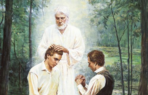 Joseph Smith, Jr. and Oliver Cowdery kneeling before John the Baptist. John the Baptist has his hands placed on the head of Joseph Smith, Jr. as he restores the Aaronic Priesthood. John is depicted wearing white. There are trees and a river in the background.