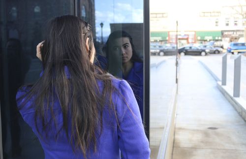 young adult woman looking at her reflection