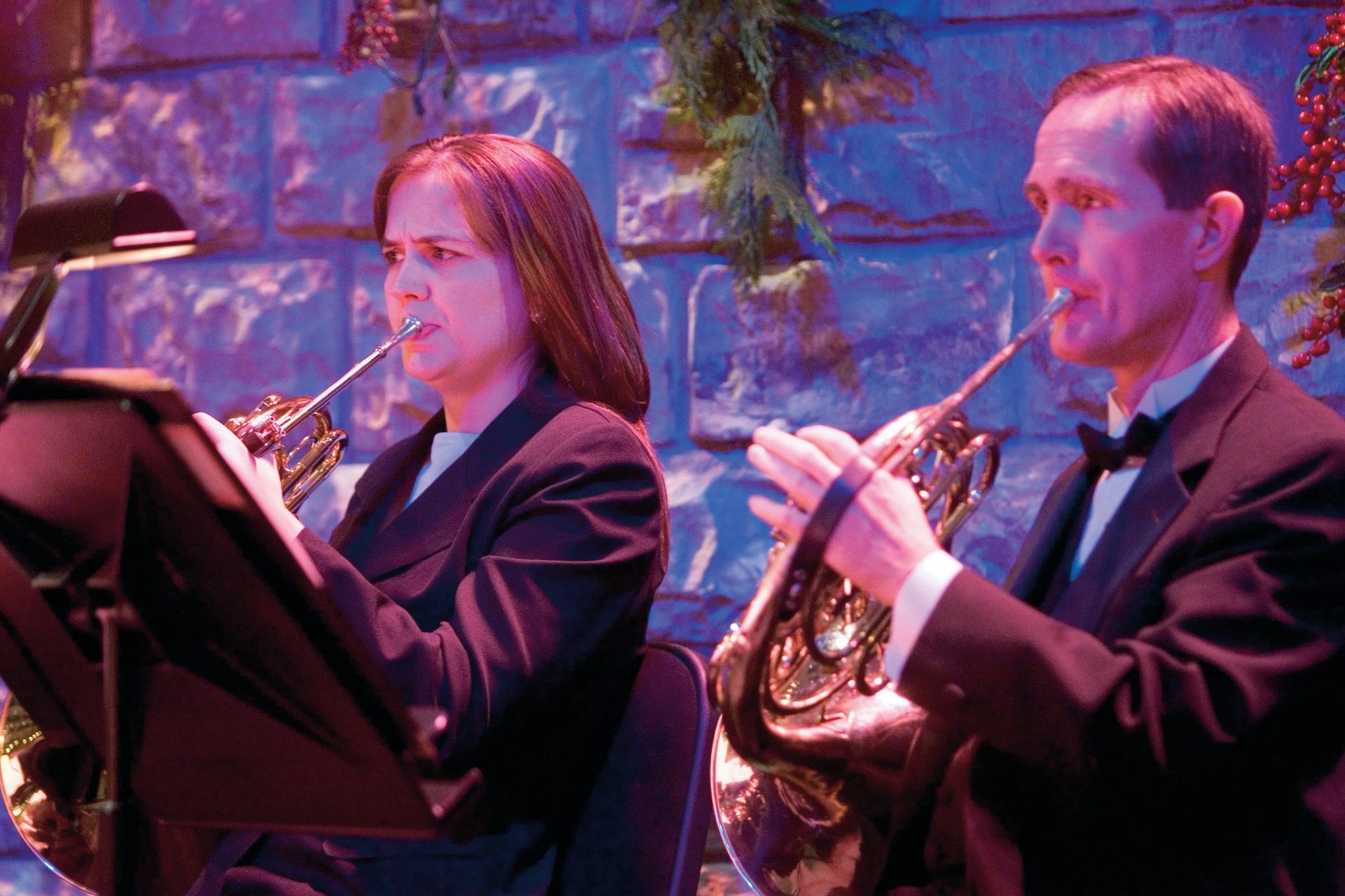 Two members of the Orchestra at Temple Square play French horns during a Christmas concert.