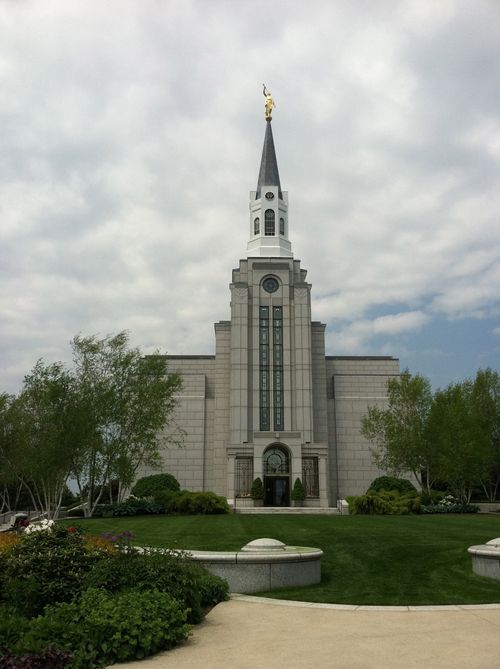 The front of the Boston Massachusetts Temple in the summer, with green grass and trees on the grounds.