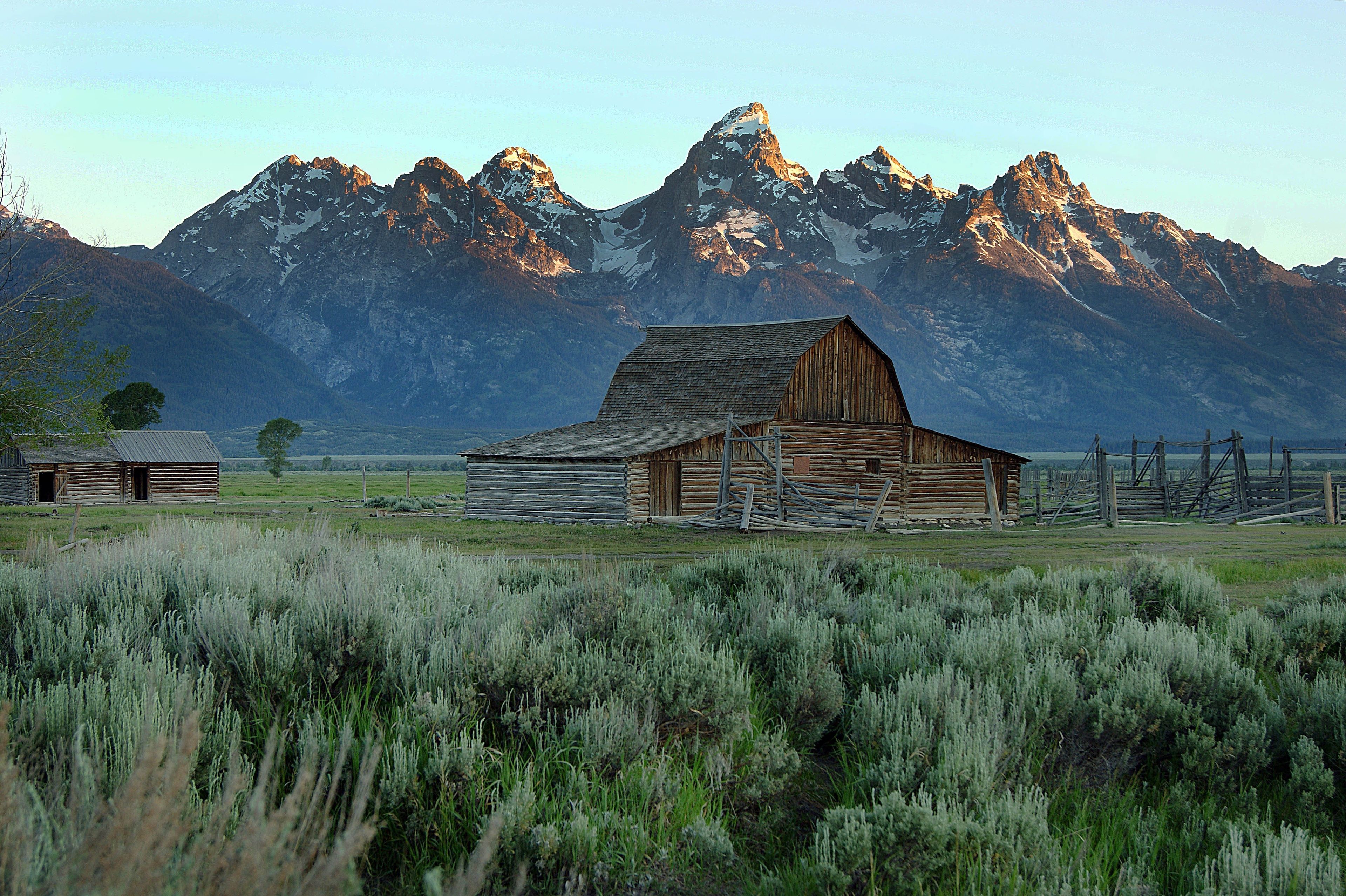 A barn with the Teton Mountains behind it.