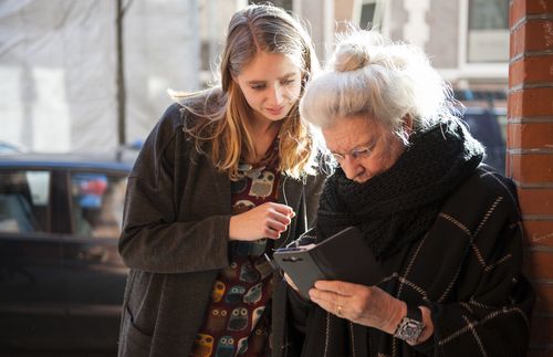 young adult woman looking at a smartphone held by an older woman