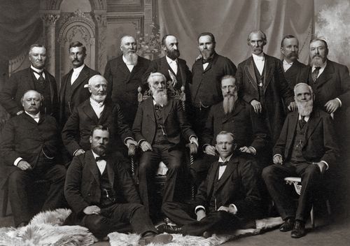 The Quorum of the Twelve Apostles in 1898, standing and sitting in three rows: Anthon H. Lund, John W. Taylor, John Henry Smith, Heber J. Grant, Brigham Young Jr., George Teasdale, Rudger Clawson, Marriner W. Merrill, Francis M. Lyman, George Q. Cannon, Lorenzo Snow, Joseph F. Smith, Franklin D. Richards, Matthias F. Cowley, and Abraham O. Woodruff.