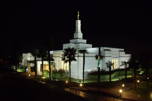 The entire Porto Alegre Brazil Temple with the lights on at night underneath a black sky.