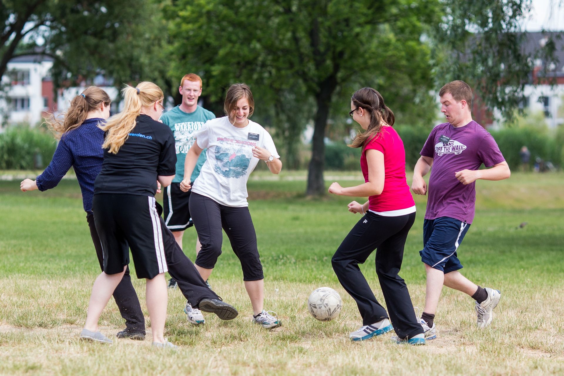 A group of missionaries play soccer in the park together.