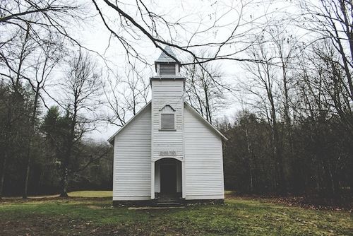 Old white church in a clearing of trees