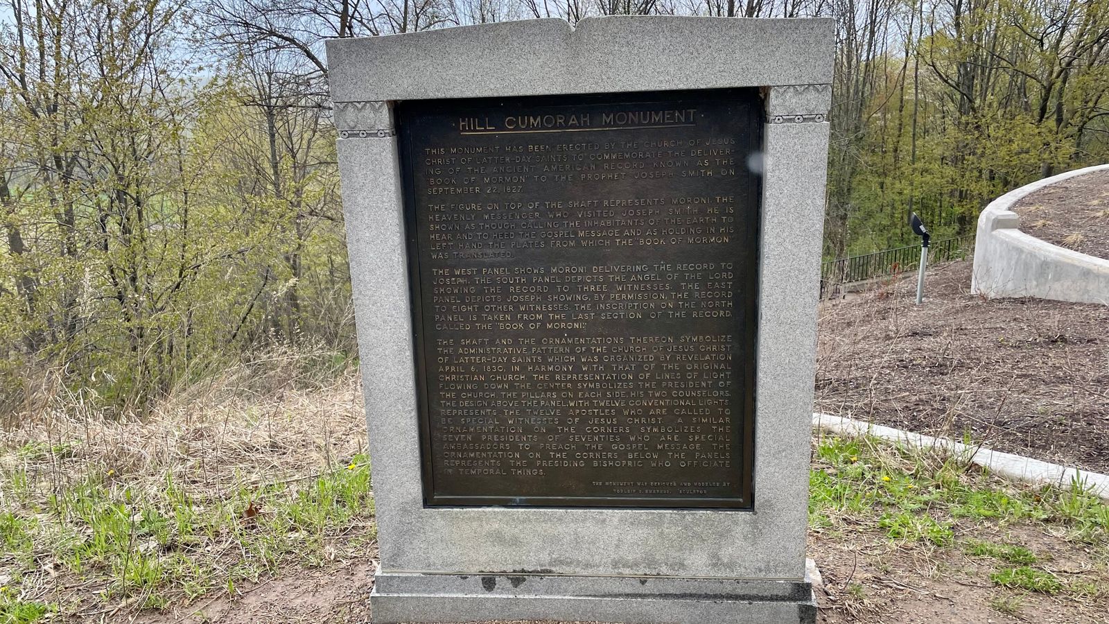 A stone monument with a metal inlay. In the metal is inscribed a description of the Hill Cumorah Monument. 