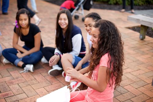 A young woman is smiling while sitting in a circle of youth at a Mutual activity in Australia.