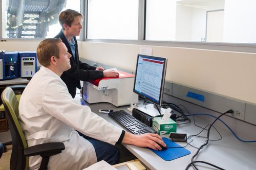 hombre con bata de laboratorio ante una computadora