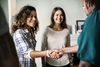 two people shaking hands smiling and a woman smiling