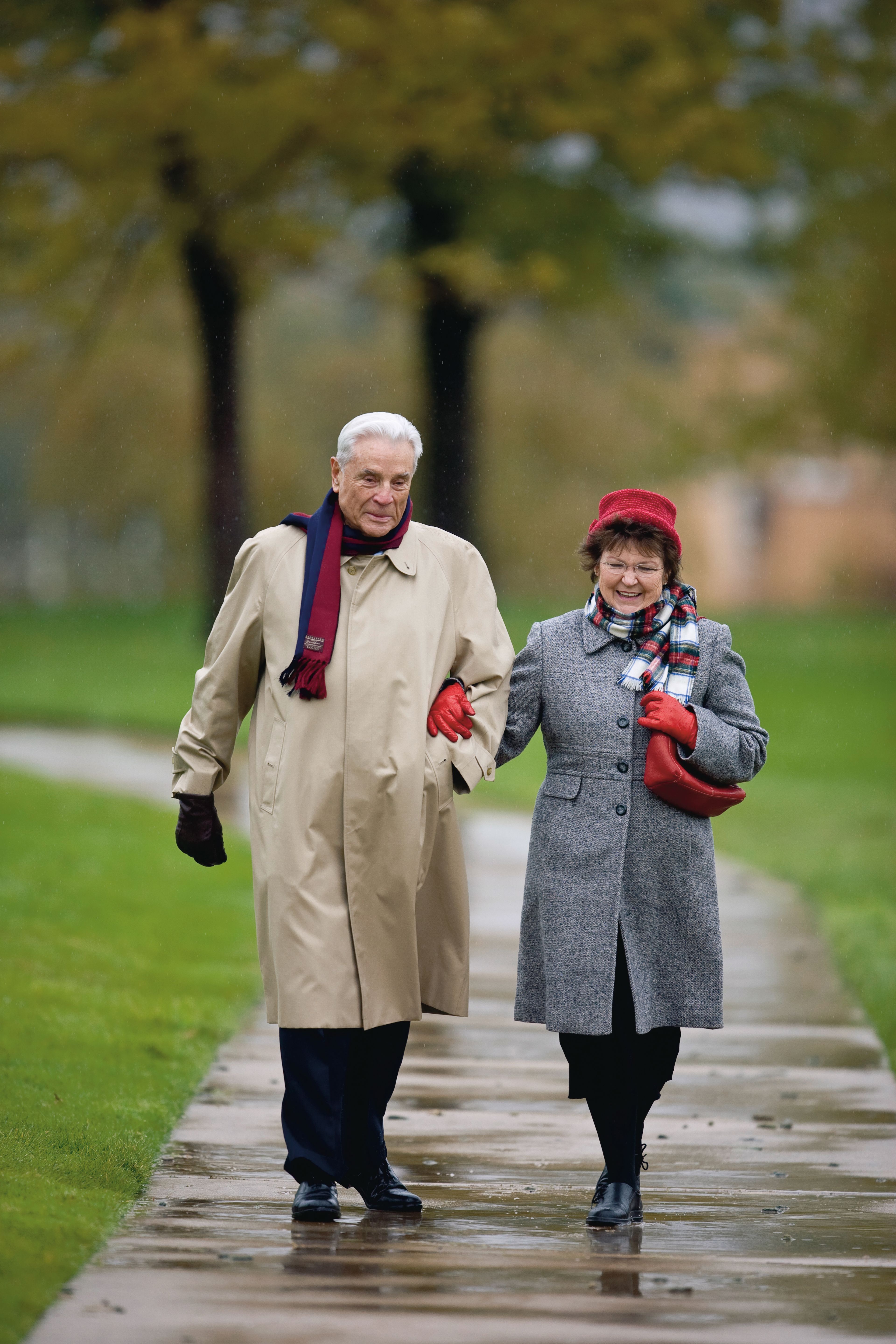 An elderly couple walking while dressed in winter clothing.