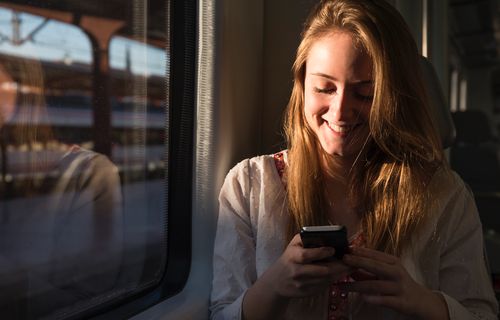 Young adult woman looking at phone on the train