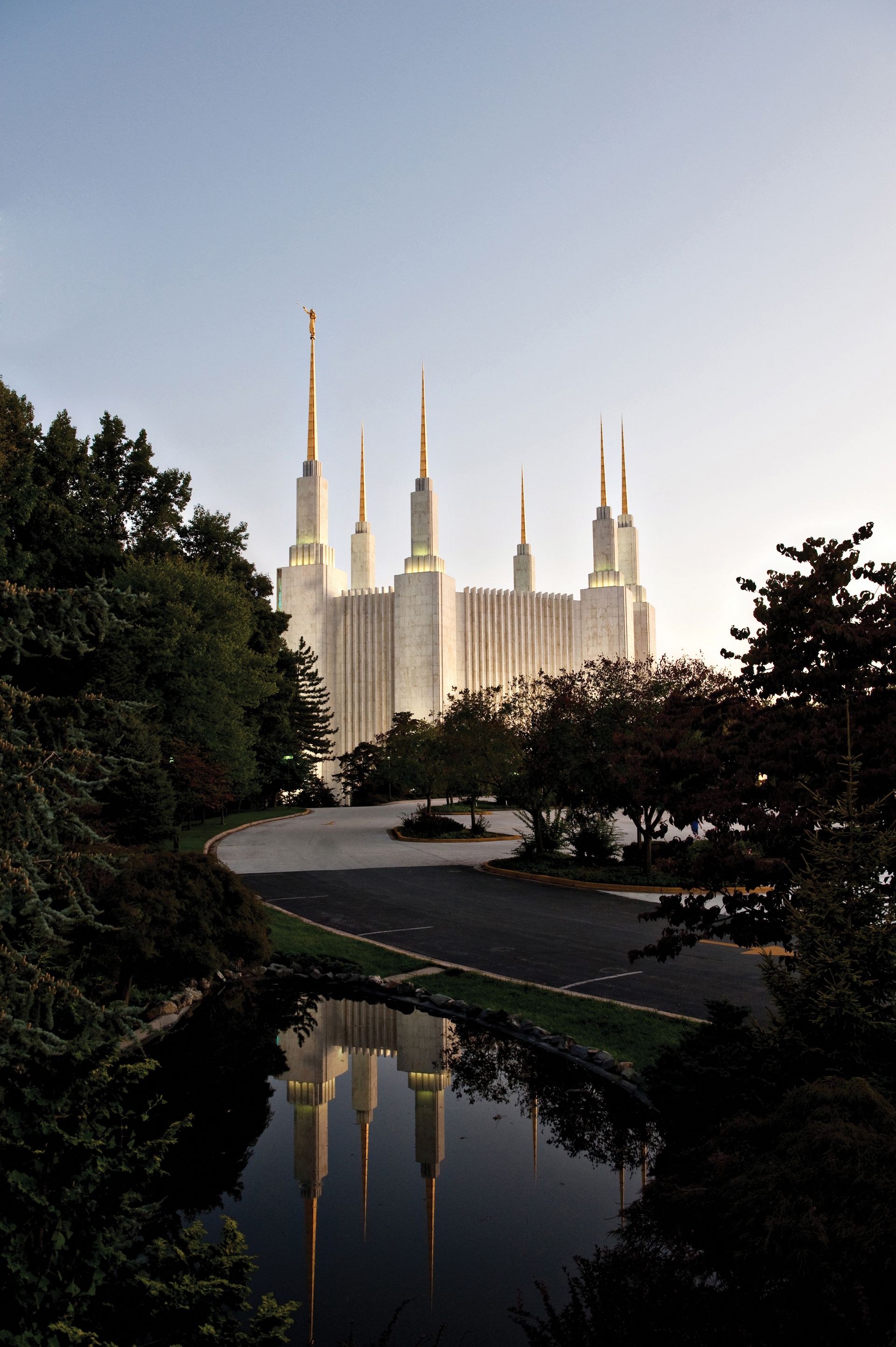 The Washington D.C. Temple during sunset, with the road and pond.