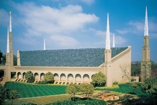 A side view from afar of the Johannesburg South Africa Temple on a sunny day, with a cloudy blue sky in the distance.