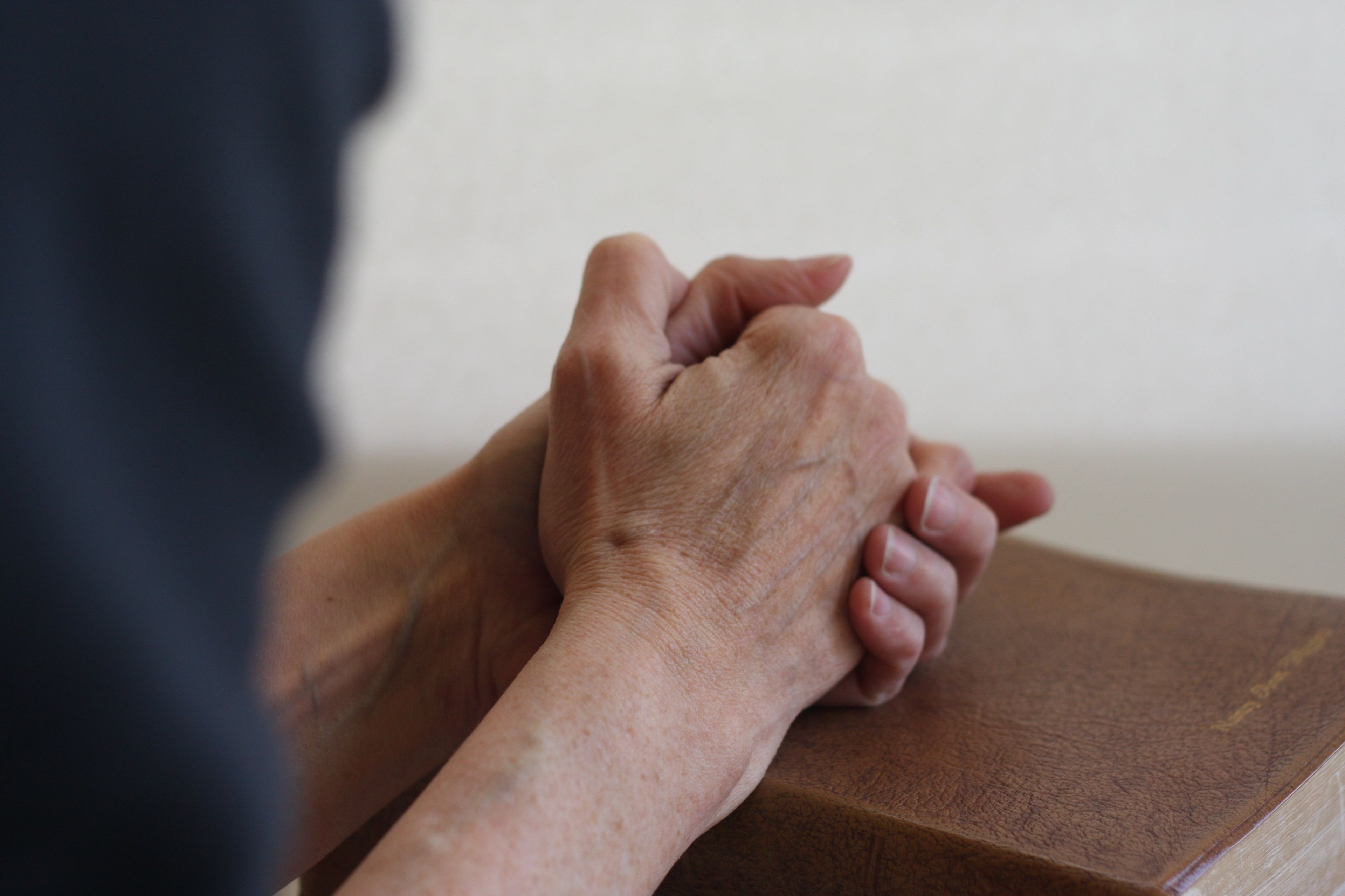 A person prays with clasped hands.