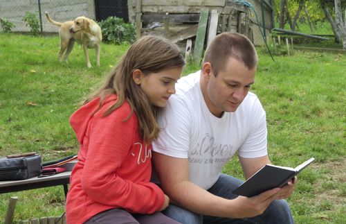 daughter and father looking at book together
