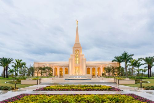 The front of the Fort Lauderdale Florida Temple in the early evening just as the lights have come on, with the fountains running near the entrance.