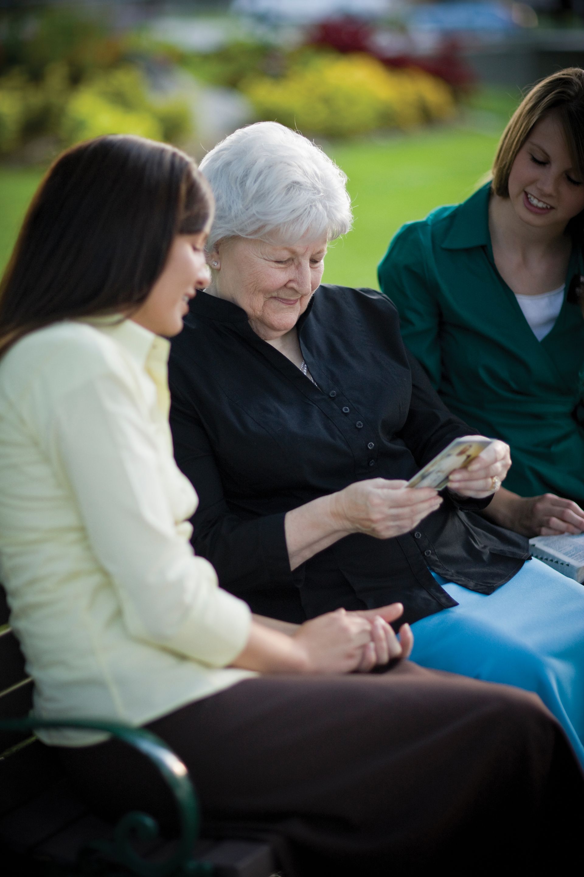 Sister missionaries giving a pass-along card to an elderly woman.