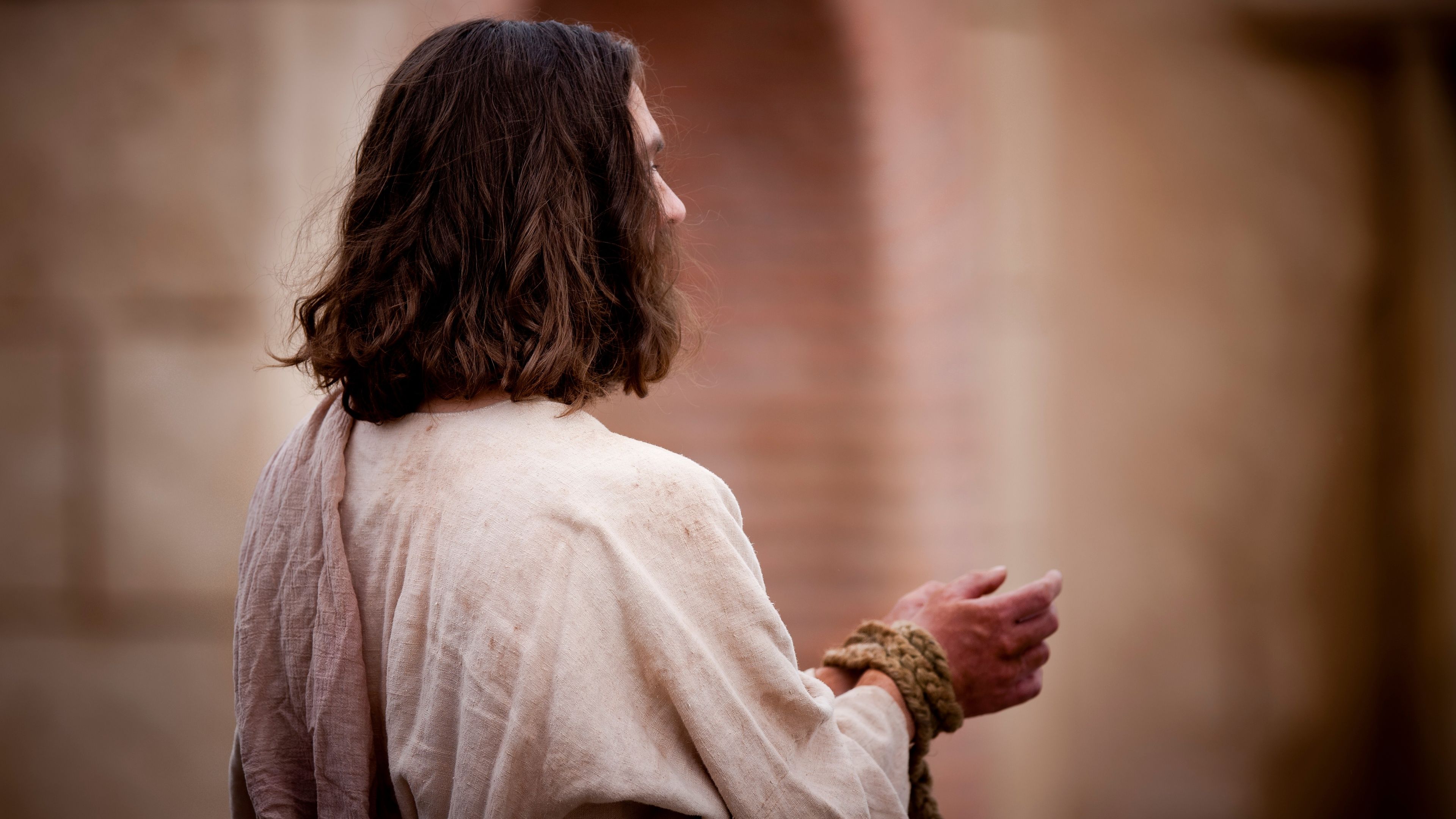 Jesus Cristo em pé com as mãos amarradas.