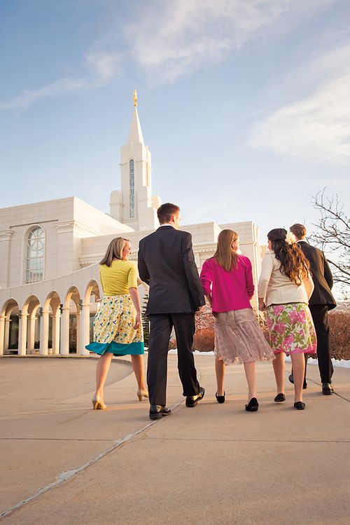 A mother and father and their three teenage children, all in Sunday dress, walk toward the Bountiful Utah Temple.