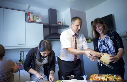 sister missionaries helping man prepare meal in kitchen