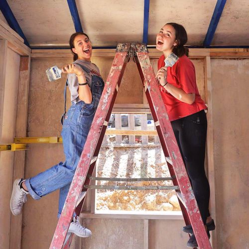 young women painting walls in new house