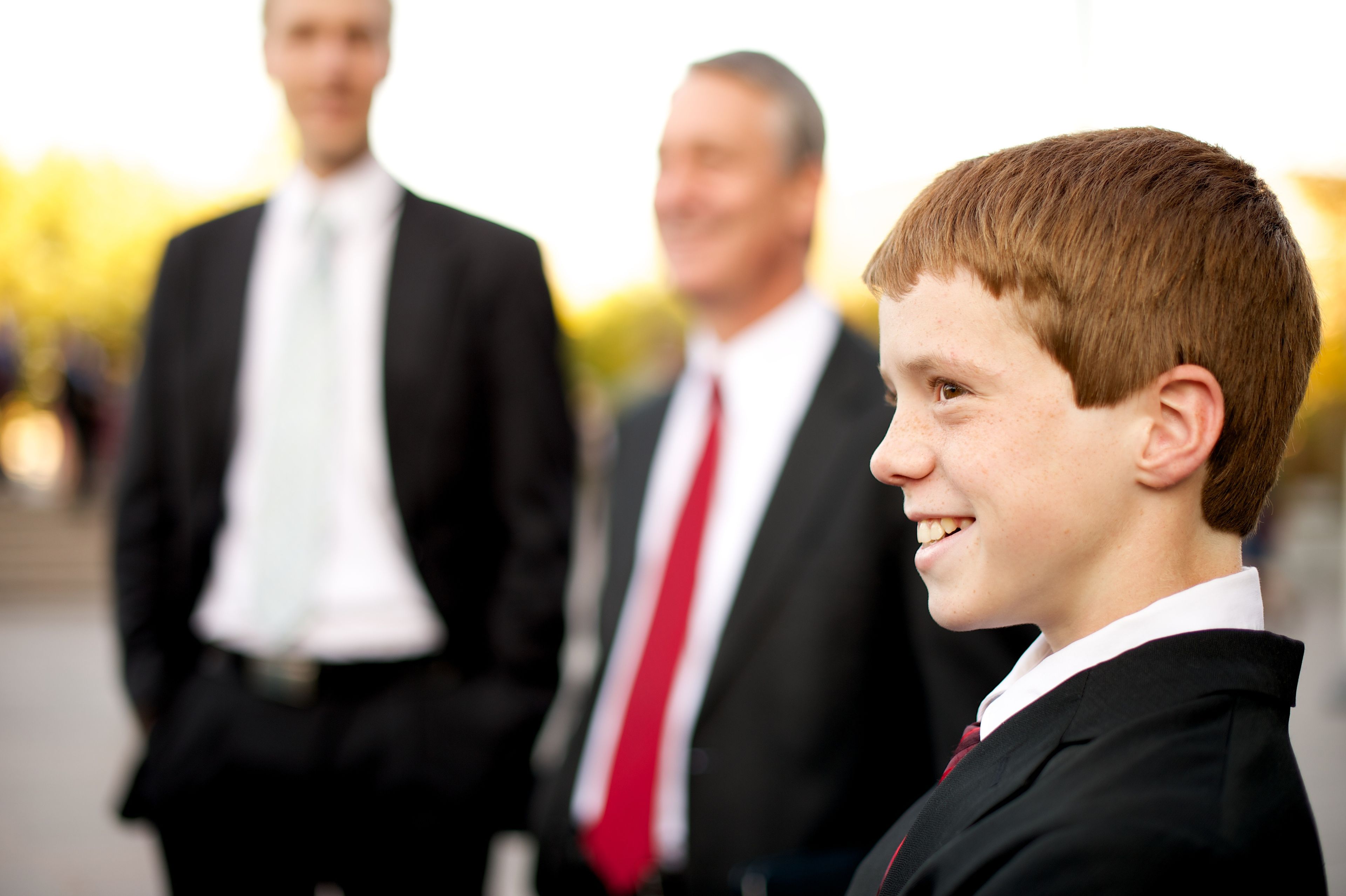 A young man in a suit stands outside of the Conference Center and smiles.