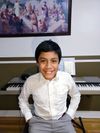 Levil Medina smiles as he sits in front of a keyboard piano.