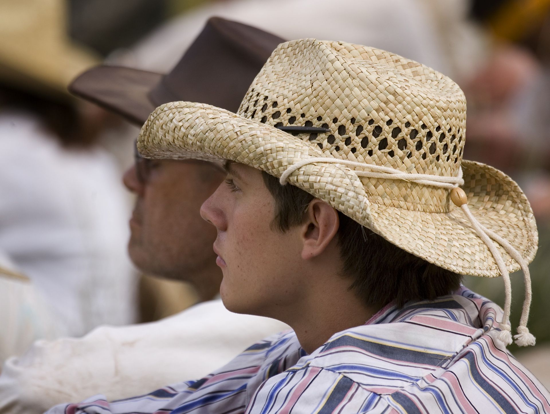 A young man wearing a straw hat sits down during trek.