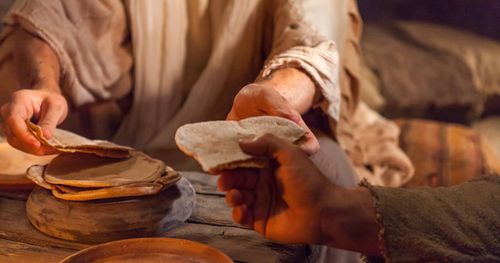 Cleopas and another disciple [possibly Luke] sitting to eat and breaking bread, and they recognize the Savior. Jesus’s hands pass the bread to one of them.