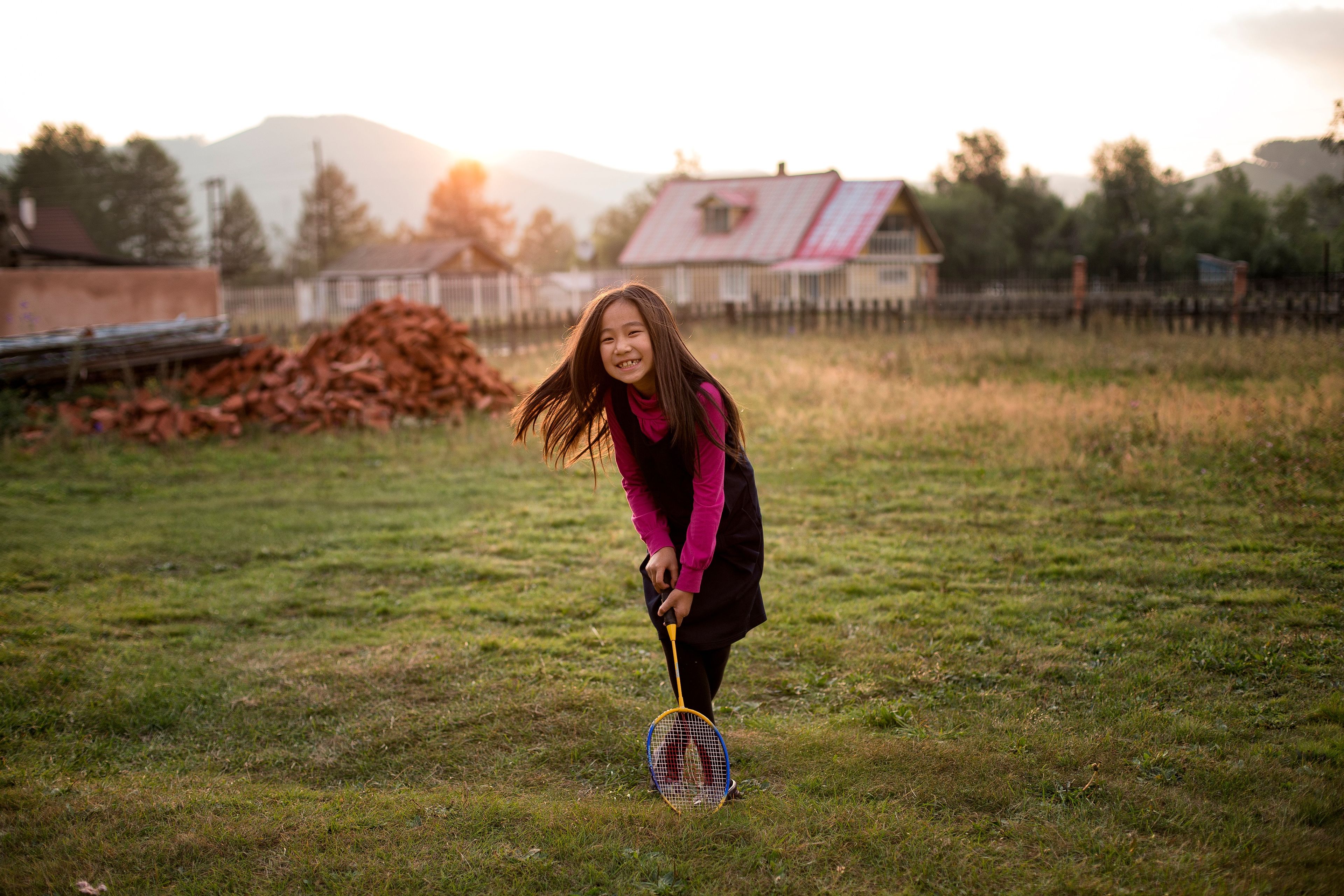 A Mongolian girl plays badminton outside.  