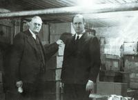 Ezra Taft Benson in Bergen, Norway.  Caption: "Inspecting welfare supplies with Pres. Petersen in mission office basement."    Collection Summary: Black-and-white views taken during Benson's February-December 1946 mission to postwar Europe to meet with Latter-day Saints, direct distribution of welfare supplies, and arrange for resumption of missionary work.