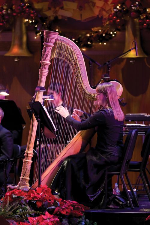 A woman with brown hair and a black dress playing a harp in the Christmas concert in 2008.